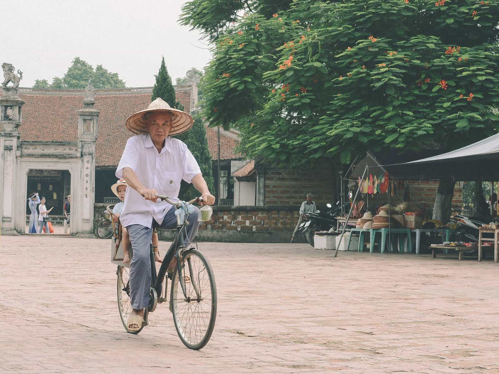 Man Riding Bike with Vietnamese conical hat on head