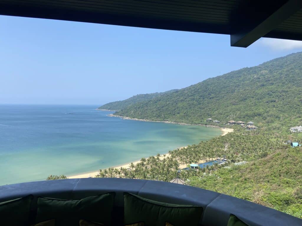 Breathtaking view from a hillside vantage point overlooking a serene tropical beach in Danang,Vietnam. The crystal-clear turquoise waters gently kiss the golden sands, while lush greenery cascades down the mountainside, inviting relaxation and exploration