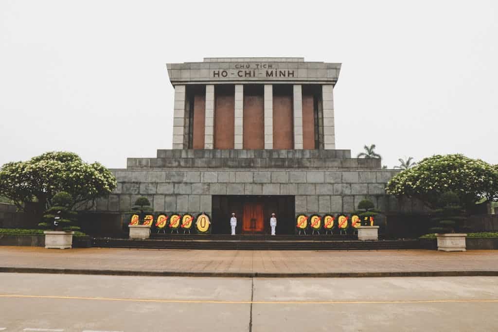Front view of the iconic Ho Chi Minh Mausoleum in Hanoi, Vietnam with guards and floral wreaths.