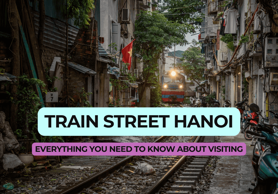 Featured image with a vibrant view of Hanoi's Train Street, showcasing a train moving down the narrow tracks surrounded by homes and greenery. Text overlay reads 'Train Street Hanoi: Everything You Need to Know About Visiting.