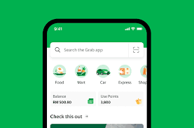 "Mobile screen displaying the Grab app interface on a green background. The app shows a search bar at the top, icons for services like Food, Mart, Car, Express, and Shop, along with a balance of RM 500.80 and available points of 3,800.